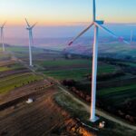 Majestic wind turbines in a vibrant landscape at sunset, showcasing renewable energy sources.