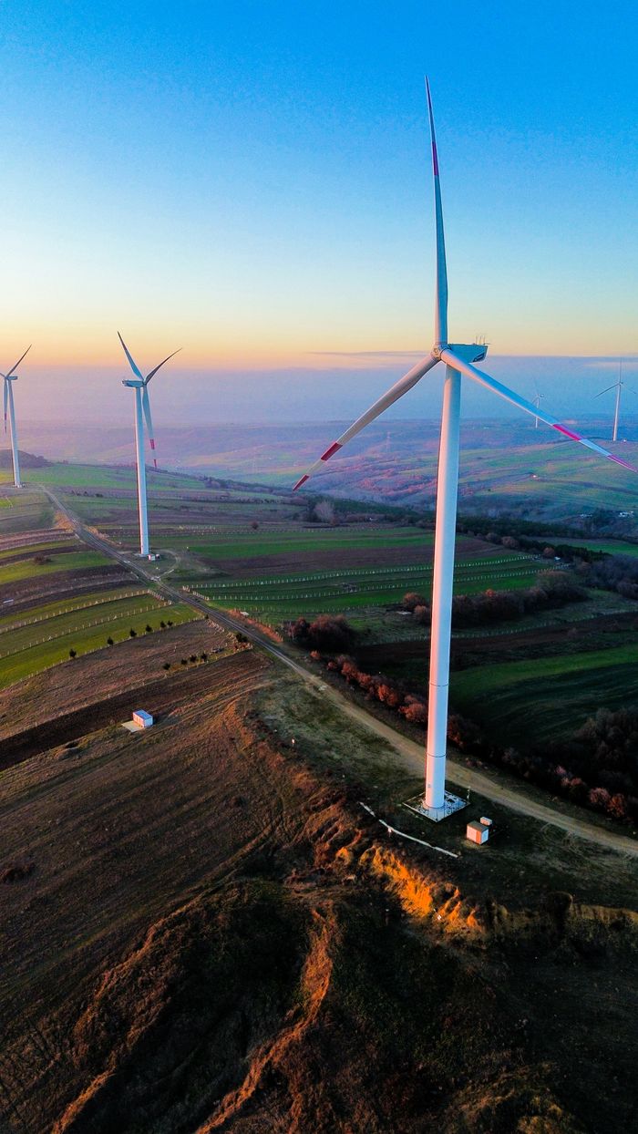 Majestic wind turbines in a vibrant landscape at sunset, showcasing renewable energy sources.